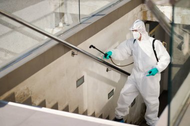 Healthcare worker in protective suit disinfecting the city during coronavirus pandemic. 