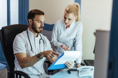 Male doctor and nurse talking while analyzing medical data in the hospital. 