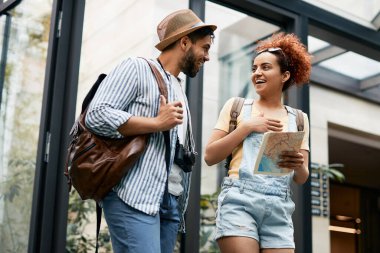 Young happy tourist couple talking to each other while arriving at their hotel. 