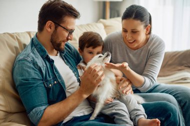 Happy parents and their son enjoying while playing wit their dog at home.