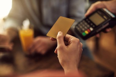 Close-up of customer making contactless payment with credit card in a cafe. 