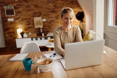 Happy female entrepreneur working on laptop at home. 