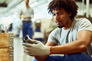 African American steel worker analyzing finished products while working in a factory. 