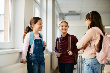 Happy elementary student and her classmates enjoying after the class and talking to each other. 