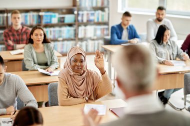 African American student in hijab raising her had to ask a question during lecture at the university.