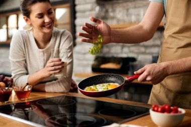 Close-up of man preparing fried eggs for breakfast in the kitchen. 