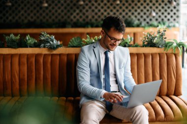 Young male entrepreneur using computer while relaxing in a cafe.
