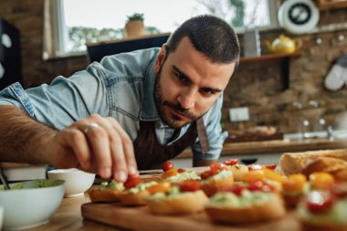 Genç adam sağlıklı yemek hazırlıyor ve mutfakta bruschetta yapıyor.. 