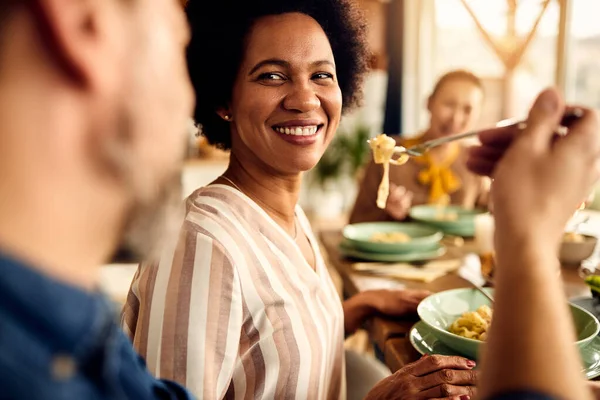 Happy Black Woman Tasting Husband Pasta While Having Lunch Friends — Stockfoto
