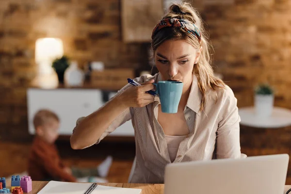Single Mother Using Laptop Having Cup Coffee While Working Home — Foto de Stock
