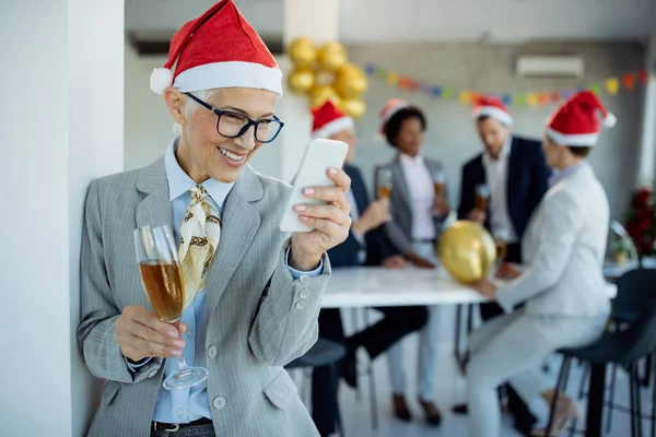 Šťastná Zralá Obchodnice Která Píše Mobil Zatímco Pije Šampaňské Silvestrovské — Stock fotografie