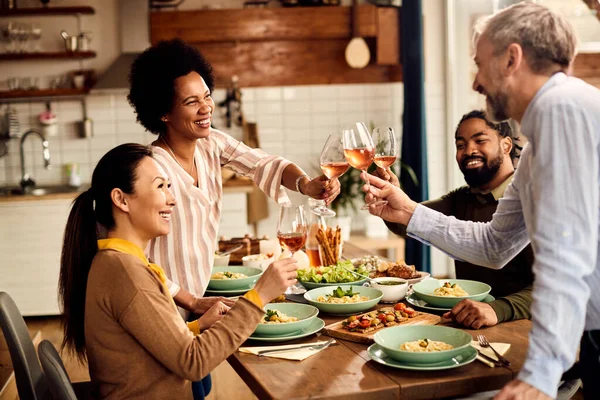 Group of happy people having fun while toasting during lunch at dining table.