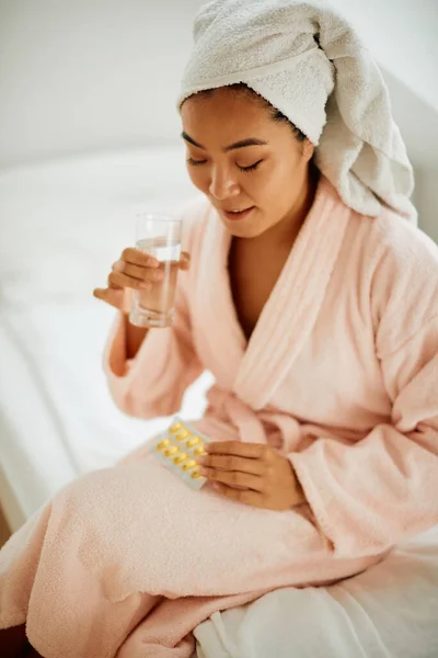 Asian woman taking care of her health and taking omega-3 fatty acid nutritional supplement at home.