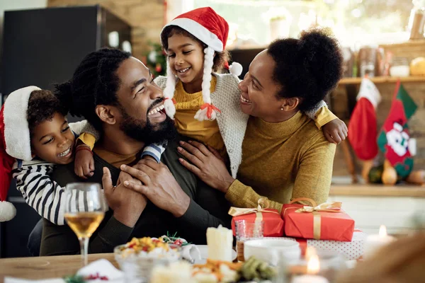 Cheerful black parents and their kids having fun while spending Christmas together at home.