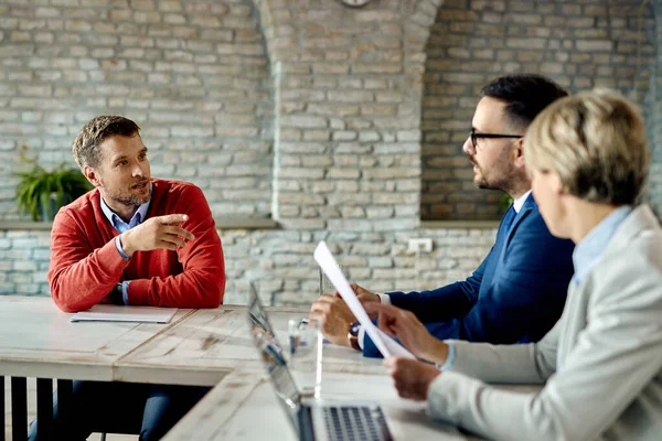 Mid adult businessman communicating with human resource team during a job interview in the office.