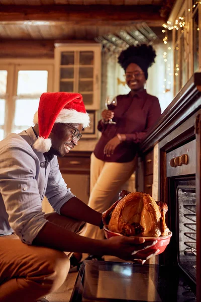 Happy African American Man Taking Roasted Turkey Out Oven While — ストック写真