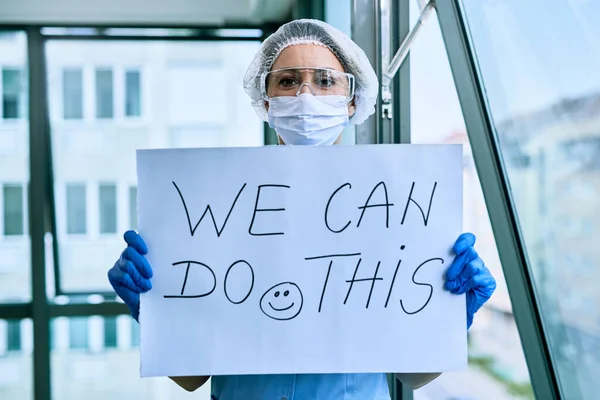 Female doctor holding placard with we can do this text as sing of a support during coronavirus epidemic.