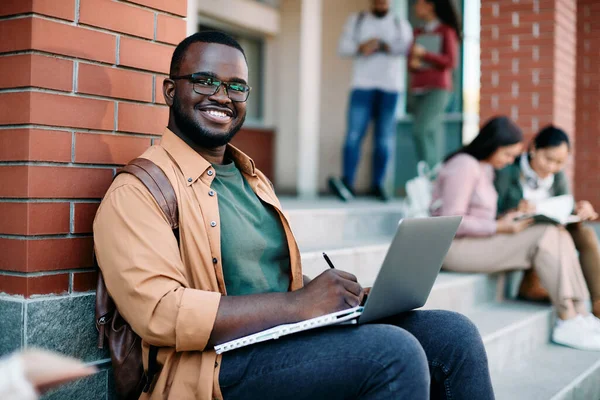 Ευτυχισμένος Αφρο Αμερικανός Φοιτητής Γράφει Σημειώσεις Ενώ Σπουδάζει Φορητό Υπολογιστή — Φωτογραφία Αρχείου
