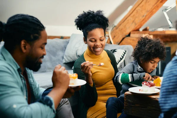 Happy African American family eating cake at home. Focus is on mother.