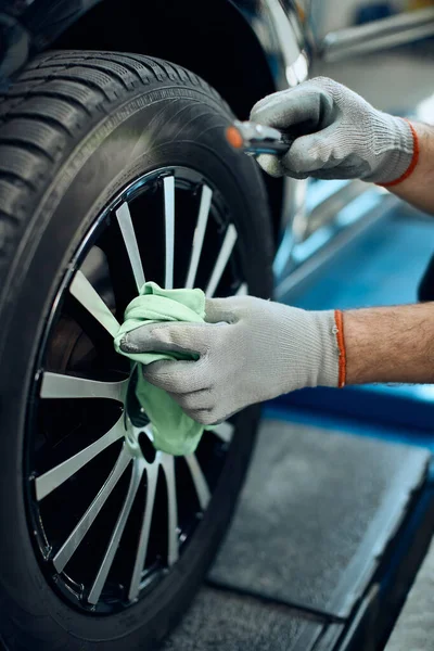 Close-up of worker cleaning tire after changing it at car service workshop.