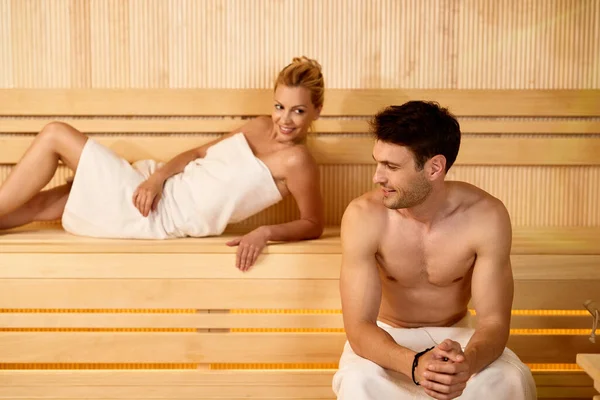 Smiling man and his wife spending a day at the spa and enjoying in a sauna.