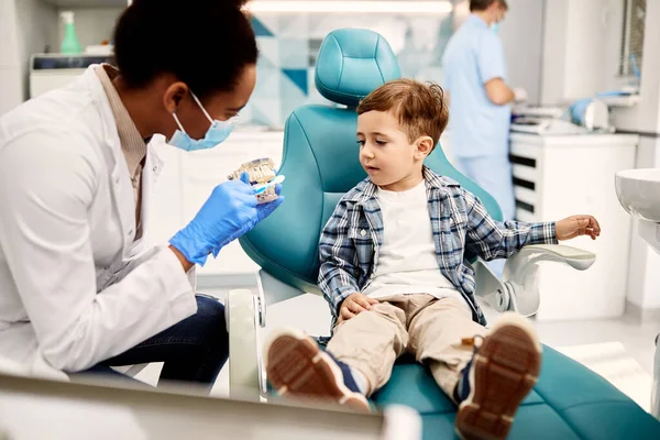 Black Female Dentist Using Denture Toothbrush While Talking Little Boy — Stock Photo, Image
