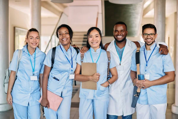 Multi0ethnic group of happy medical and nursing students standing in a hallway at medical university and looking at camera.
