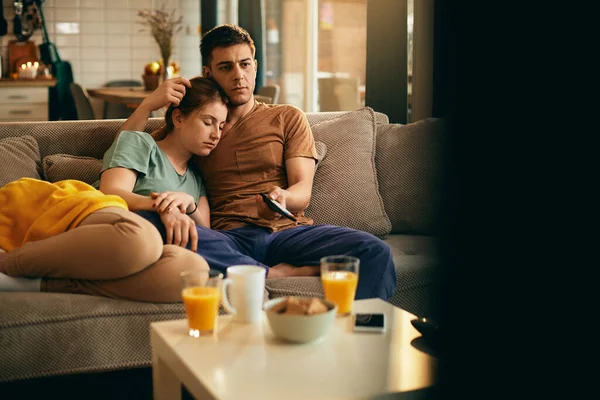 Young woman taking a nap while watching TV with her boyfriend at home. Copy space.