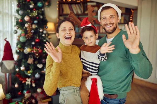 Joyful family having fun while celebrating Christmas and waving to camera.