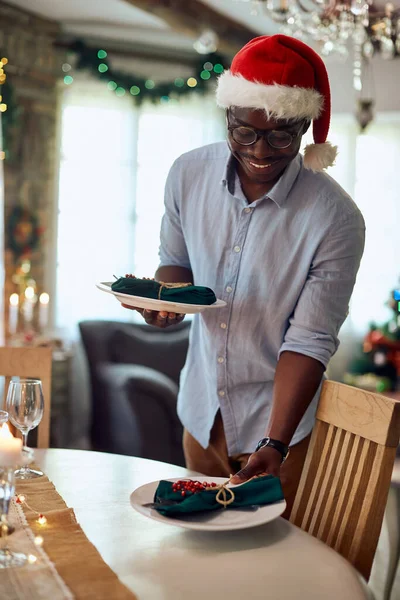 Happy Black Man Enjoying Decorating Dining Table Christmas Meal Home — Foto Stock