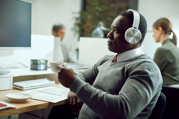 African American Businessman Wearing Headphones While Using Computer Having Cup — Zdjęcie stockowe