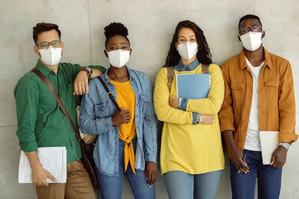 Multi-ethnic group of university friends with protective face masks against the wall.