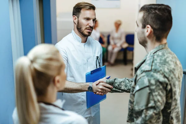 Young Doctor Talking Soldier While Greeting Him Lobby Clinic — ストック写真