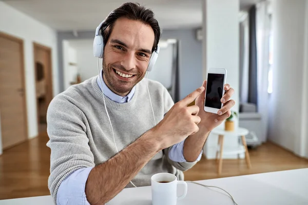 Happy Freelance Worker Wearing Headphones Pointing Cell Phone Screen While — Stok fotoğraf