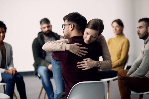Young couple embracing as a part of activity of group therapy. 