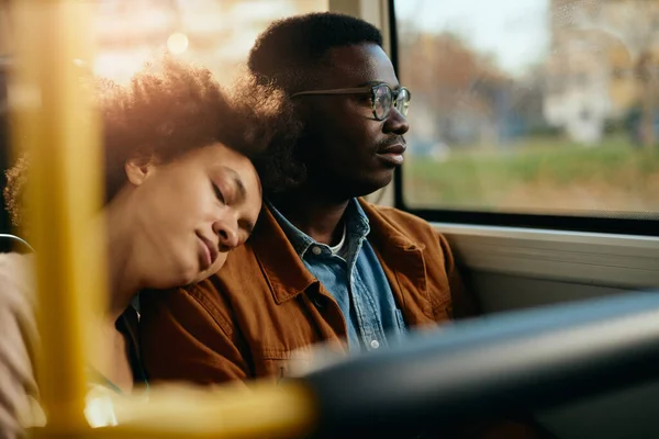 Pensive Black Man Looking Window While His Girlfriend Fell Asleep 图库图片