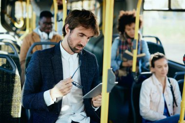 Male entrepreneur using digital tablet while traveling to work by public transport.  