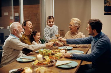 Happy multi-generation family having fun while toasting at dining table.