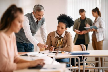 African American woman studying with help of her teacher during a class at lecture hall. 