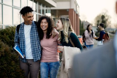 Multi-ethnic group of college friends having fun after the lecture at campus.