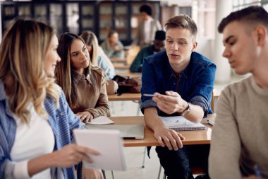 Male student talking to his friends during lecture in the classroom. 