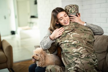 Young happy woman embracing her military husband who came home from war. 