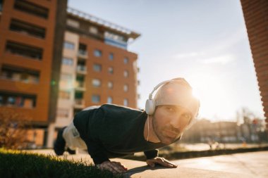Young athletic man doing push-ups while exercising in the city. 