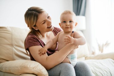 Young caring mother enjoying in time with her cute baby boy at home.