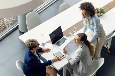 Toplantı sırasında iş grafiğini incelerken iletişim kuran kadın girişimcilerin yüksek açılı görünümü. 