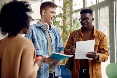 Smiling African American student and his friend analyzing exam results in a hallway at the university. 