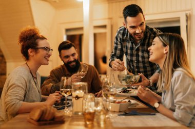 Young happy people eating dinner and having fun at dining table at home. 