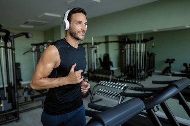 Young smiling athlete jogging on running track during sports training in health club. 