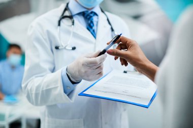 Close-up of woman signing medical agreement before dental procedure at dentist's office.