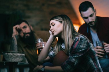 Group of sport fans feeling sad after their team has lost a game. Focus is on woman.